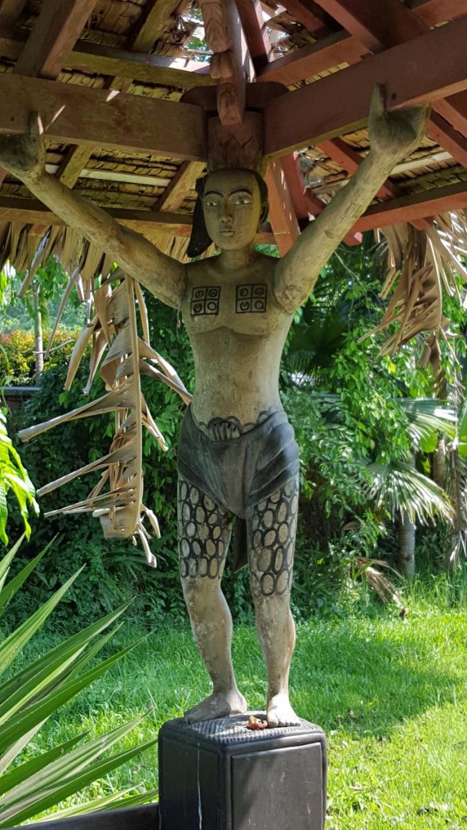 Proud figure holding the roof of a lake pavilion at SEEDS property 